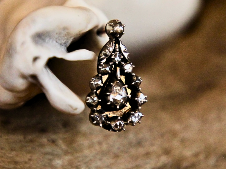 A close up image of one of a pair of Georgian Diamond Earrings. The earring is tear drop in shape with 16 rose-cut diamonds.