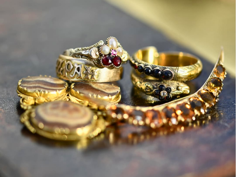 a-pin-of-gold-ring-collection A photograph of a woman's neck and shoulders wearing a gold Georgian high-carat fist pendant and chain.